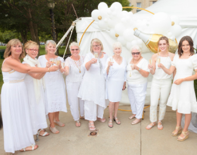 The planning committee members dressed all in white making a champagne toast